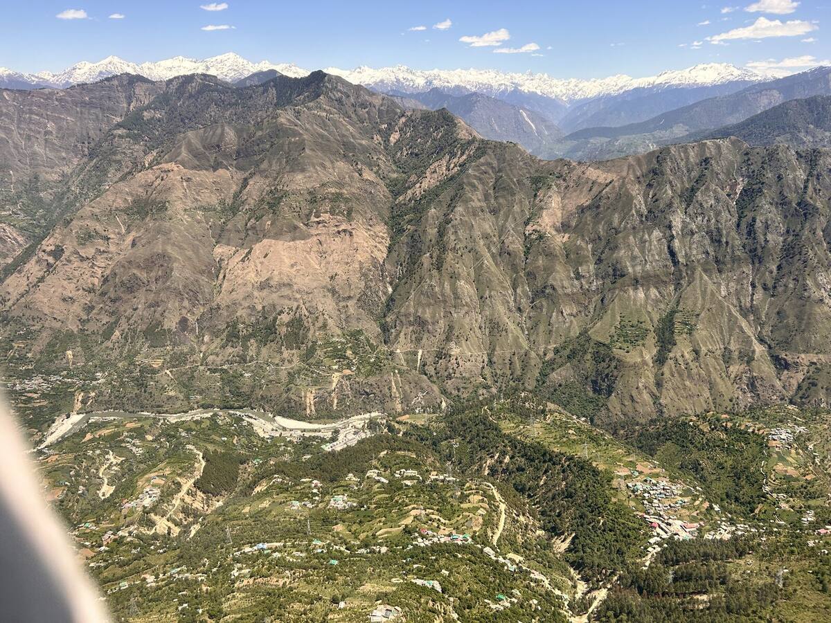 Brown denuded slopes against snow-capped peaks in Himachal Pradesh