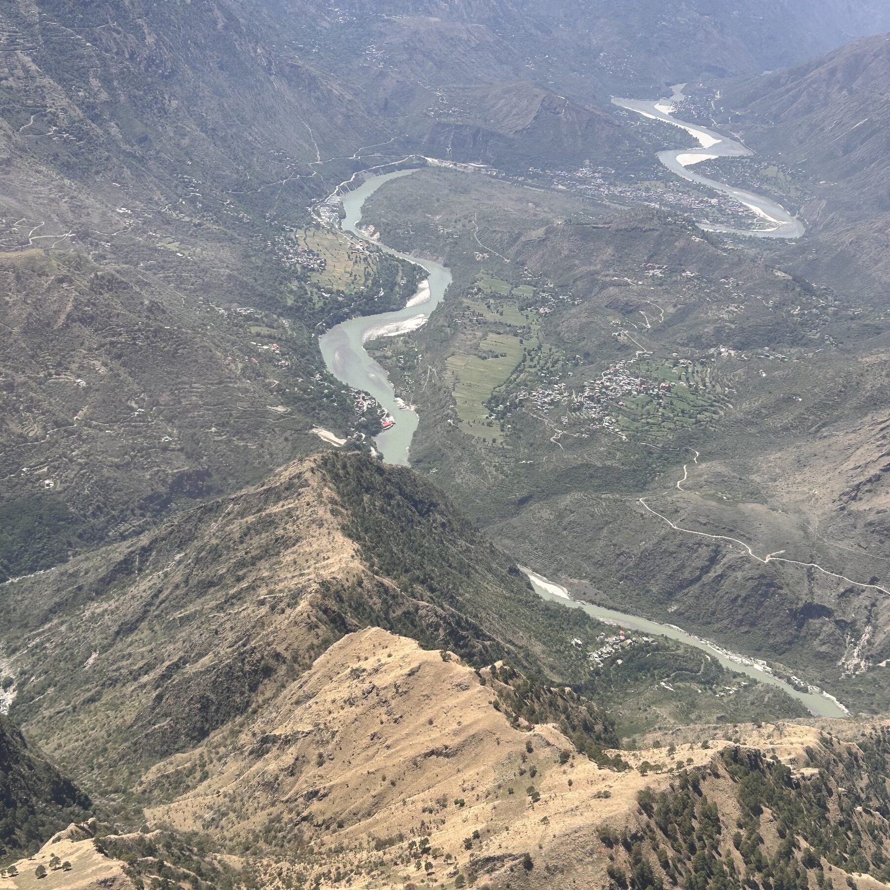 Aerial view of a Himalayan river gorge with terraced villages clinging to fragile slopes, Himachal Pradesh